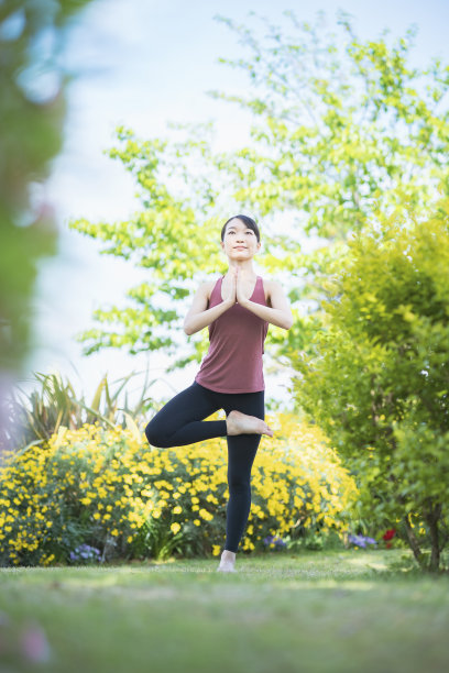一个年轻女子在绿色公园里做瑜伽图片下载