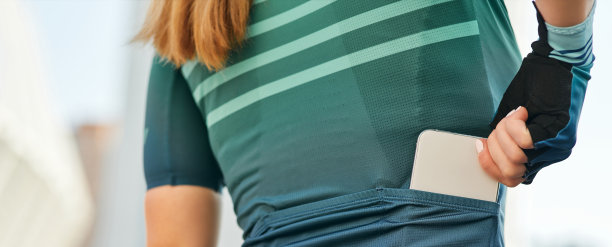 职业女自行车手在运动服把她的手机放在衣服的拉链口袋的特写网站标题图片下载