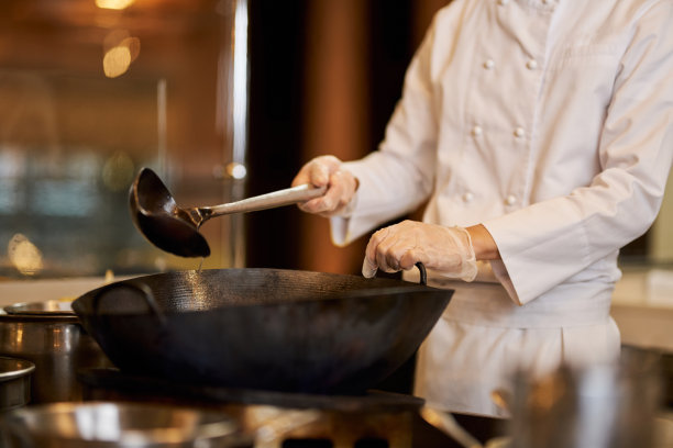 熟练的厨师用勺子热锅图片下载