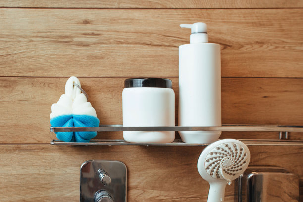 在一间有木墙的浴室里，架子上放着一块沐浴海绵、一瓶洗发水和发胶。浴缸和淋浴概念图片下载