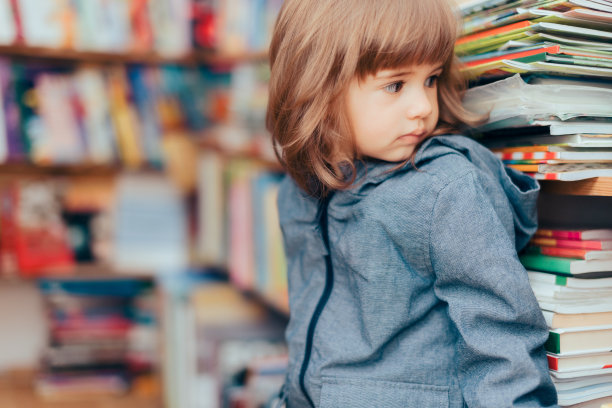 快乐顽皮的小女孩站在图书馆里图片下载