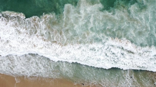 从上到下的鸟瞰图的冲击海浪在海岸线上图片下载