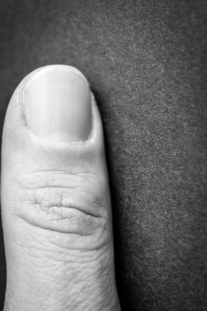 标题:一个男人的拇指微距照片，指甲和皮肤纹理在黑色背景图片下载