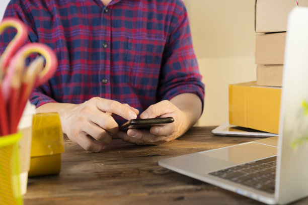 商人用智能手机思考成堆的包裹放在办公桌上图片下载