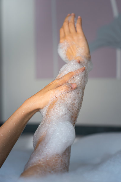 用沾有沐浴泡沫的手轻拍手臂-美容保健活动照片。图片下载