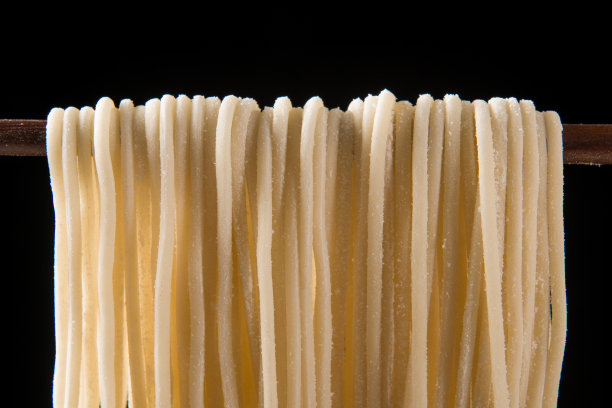 筷子旁的生面条孤立在黑色背景上。图片下载