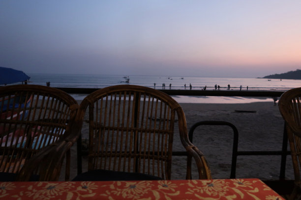 夜间图像的餐厅桌子和椅子准备露天用餐与海滩的景色，俯瞰Palolem海滩和阿拉伯海，果阿，印度南部图片下载