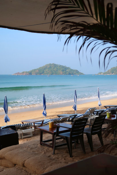 餐厅的餐桌和椅子为户外用餐准备好了海滩的景色，俯瞰帕洛伦海滩和阿拉伯海的阳伞和躺椅，印度南部果阿图片下载