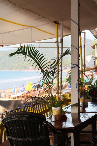 餐厅的餐桌和椅子为户外用餐准备好了海滩的景色，俯瞰帕洛伦海滩和阿拉伯海的阳伞和躺椅，印度南部果阿图片下载