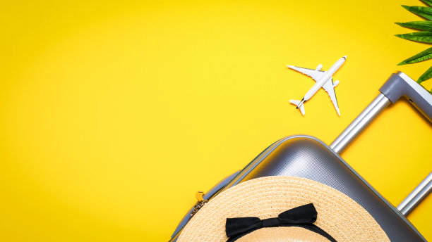 旅行箱，棕叶草帽太阳镜，黄色背景上的白色飞机。暑假暑假概念设计。图片下载