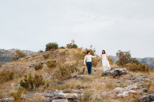 新娘和新郎走下山坡。新郎牵着新娘的手图片下载
