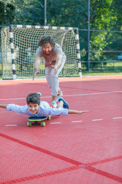 小男孩和他的爸爸在公园玩滑板。图片下载
