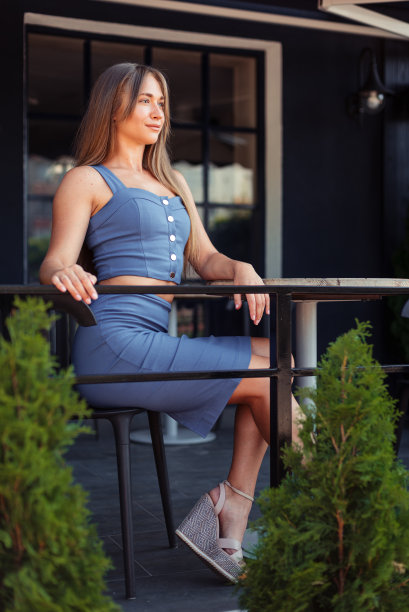 咖啡厅里一个女孩的垂直照片。一个穿蓝色上衣的女孩侧身坐着。图片下载