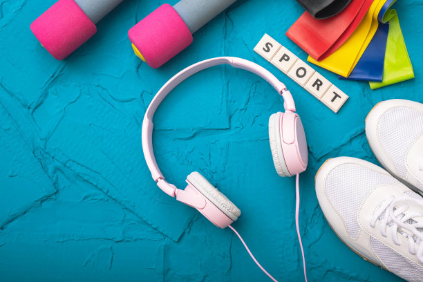 在家运动——白色运动鞋，哑铃和橡皮筋，蓝色背景上放着耳机图片下载