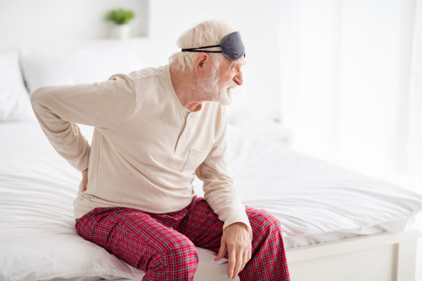 一位老人的侧面照片，坐在不好的手在脊椎上，痉挛伤脊椎，不开心，不舒服，在室内看空图片下载