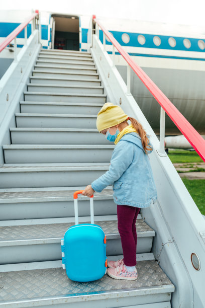 小女孩戴着防护口罩，提着行李箱上了飞机图片下载