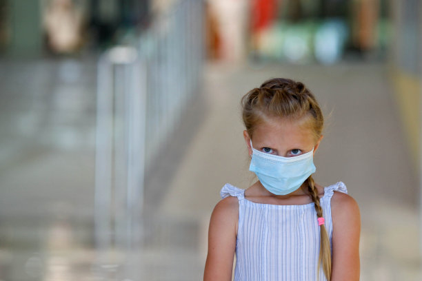 戴口罩的欧洲小女孩，保护pm2.5和Covid-19。在模糊的背景下，一个戴着医用口罩的小女孩。本空间图片下载
