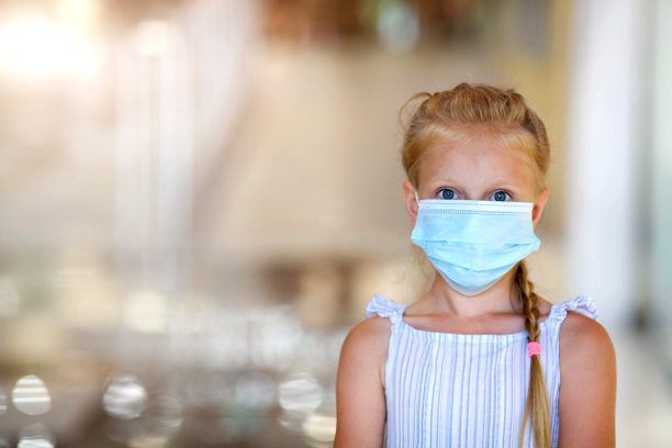 戴口罩的欧洲小女孩，保护pm2.5和Covid-19。在模糊的背景下，一个戴着医用口罩的小女孩。本空间图片下载