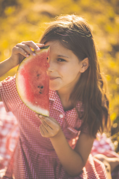 该吃水果了。小女孩拿着一片西瓜。图片下载
