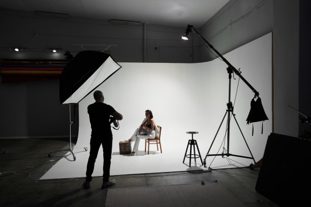 摄影工作室里的时尚摄影。专业男摄影师在后台为美丽的女模特拍照图片下载