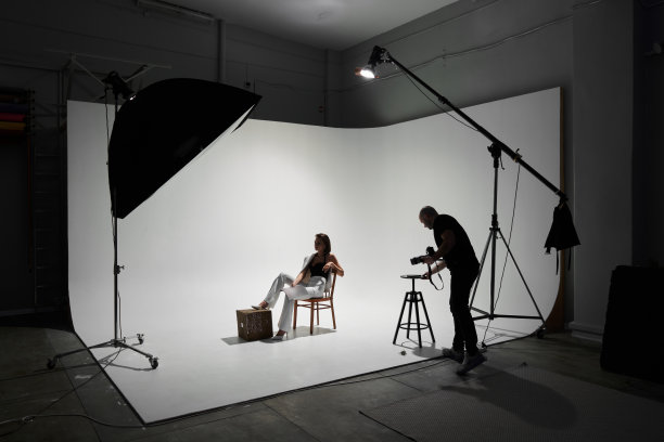 摄影工作室里的时尚摄影。专业男摄影师在后台为美丽的女模特拍照图片下载