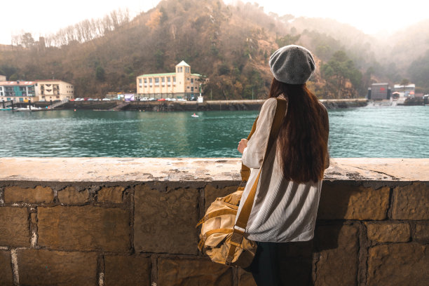 一个年轻的白人女人在河边参观一个古老的小镇图片下载