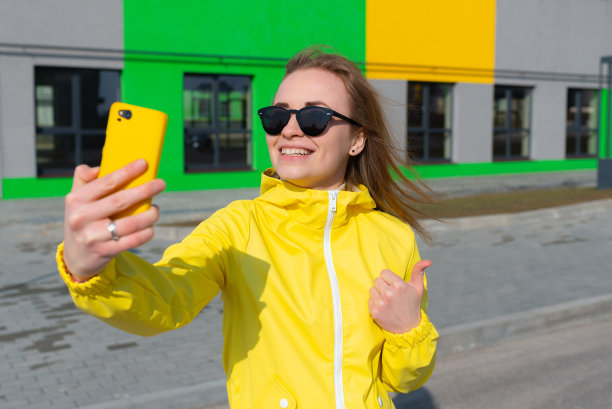 一幅时尚红发女孩戴着墨镜用智能手机自拍的照片图片下载