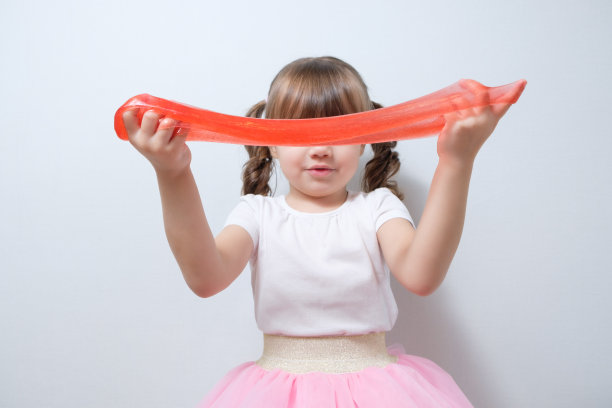 小女孩用黏液玩红色闪光。受欢迎的爱好,DIY图片下载