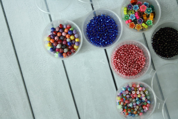 彩色珠子装在圆形的塑料盒子里，在木制的背景上。图片下载