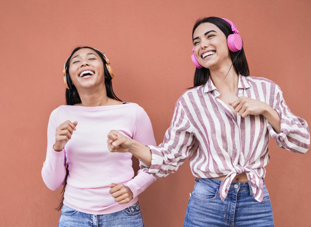 年轻的拉丁女孩带着无线耳机在户外跳舞，她们在城市里一起玩乐图片下载