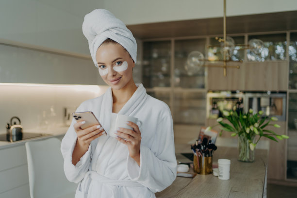 幸福的女人在浴衣和毛巾在头上放松与一杯茶，同时做美容程序在家里图片下载