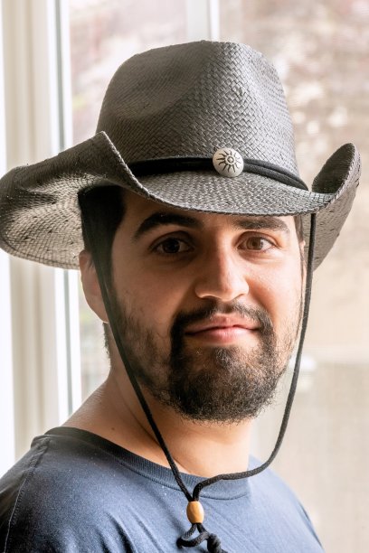 年轻的西班牙裔农业工人移民看着窗户旁的摄像机摆姿势图片下载