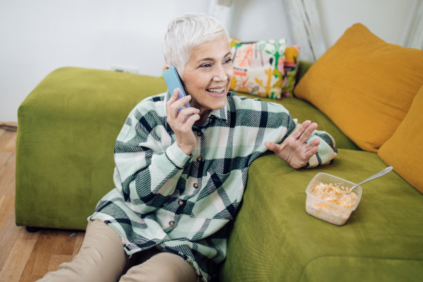 一个成熟女人在吃早餐时打电话的照片图片下载