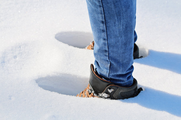 一个人走在雪地里，脚印在雪地里，雪很深，雪堆上。图片下载