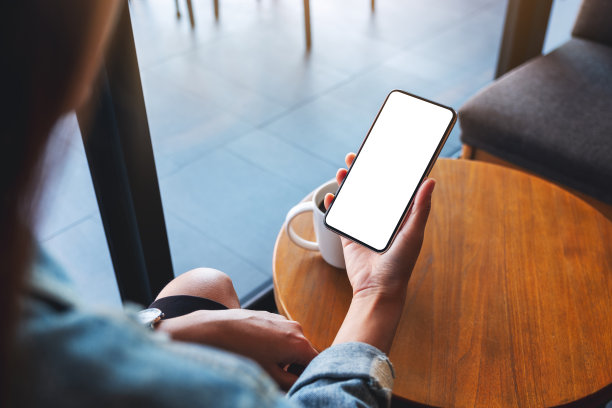 一个女人拿着手机和空白的白色桌面屏幕图片下载