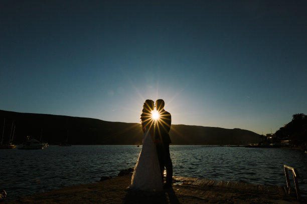 日落时分，新郎和新娘手牵着手站在海边图片下载