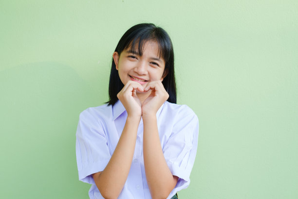 肖像学生年轻女孩在校服上的绿色背景，亚洲女孩，青少年。图片下载