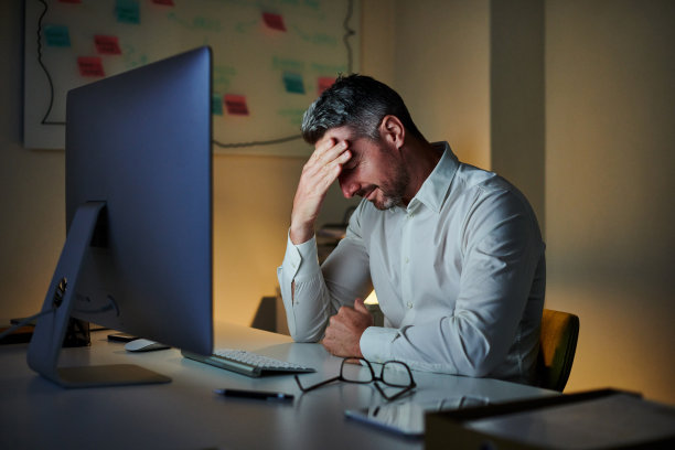 这是一个成熟的商人晚上在办公室电脑前工作时看起来很紧张的照片图片下载