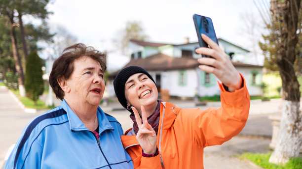 快乐的祖母和孙女用智能手机自拍的照片。户外。国际老年人日图片下载