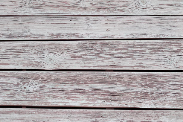 背景是一面墙的纹理，大木板涂着白色的油漆，有时剥落成柔和的颜色和粉红色的白色飞溅。高质量的照片图片下载