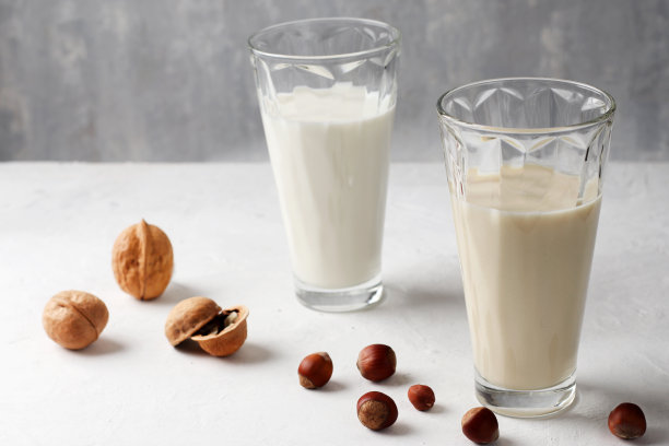 在玻璃杯中，坚果牛奶在一个轻的背景。有机天然素食饮料。健康的概念。图片下载