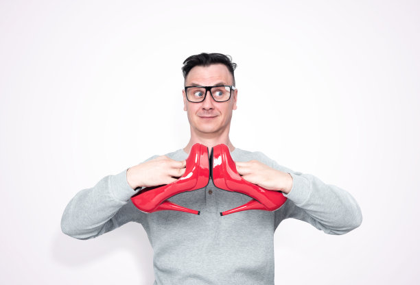 滑稽的男人戴眼镜，拿着红色高跟鞋的女人，孤立在光背景。图片下载