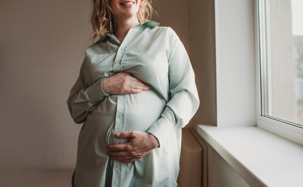漂亮的怀孕女孩站在窗边图片下载