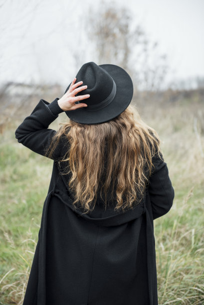 年轻迷人的女人的肖像穿着黑色大衣和帽子。图片下载