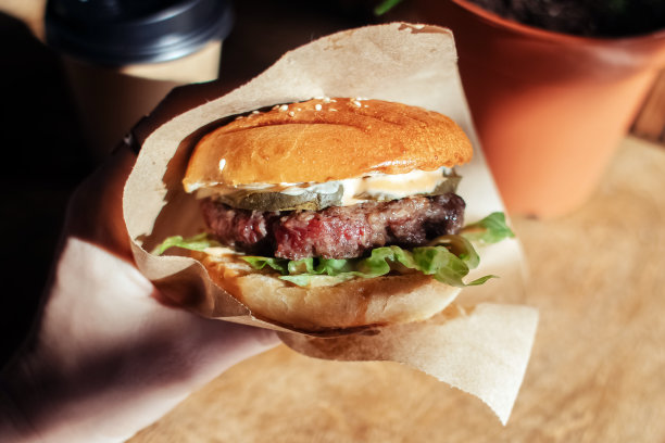 汉堡在纸包装特写。快餐店里的食物。汉堡配料与肉和蔬菜的微距照片图片下载