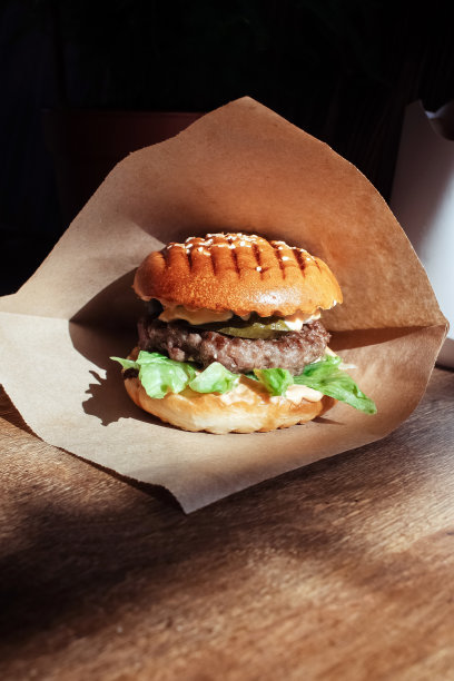 汉堡在纸包装特写。快餐店里的食物。汉堡配料与肉和蔬菜的微距照片图片下载