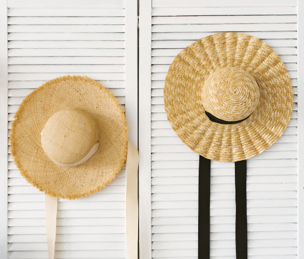 木质屏风与草帽的背景白色砖墙与复制空间。在冠状病毒疫情期间，旅行被延误。图片下载