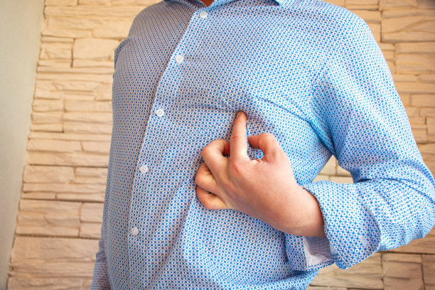 人指着左侧胸部的乳头。男女乳头疼痛、男性乳房发育、乳腺疾病和病理改变的概念照片图片下载