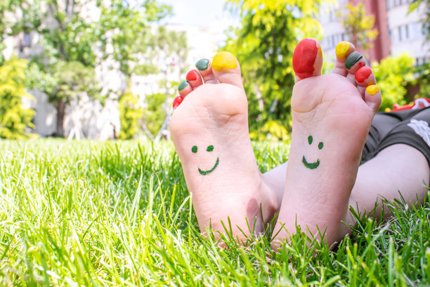 孩子们的脚上画着一幅微笑的绿色草地。有选择性的重点。图片下载