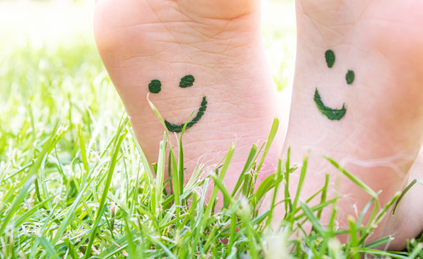 孩子们的脚上画着一幅微笑的绿色草地。有选择性的重点。图片下载